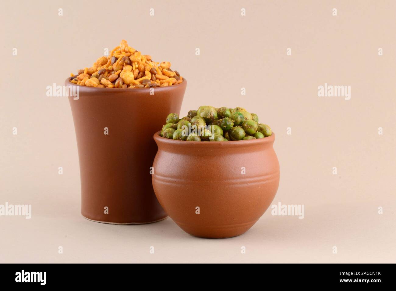 Indian snack: miscela e fritti speziati piselli verdi {chatpata mataró} in pentole di creta. Foto Stock