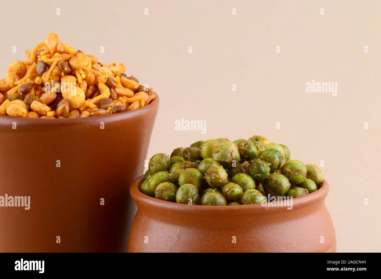 Indian snack: miscela e fritti speziati piselli verdi {chatpata mataró} in pentole di creta. Foto Stock