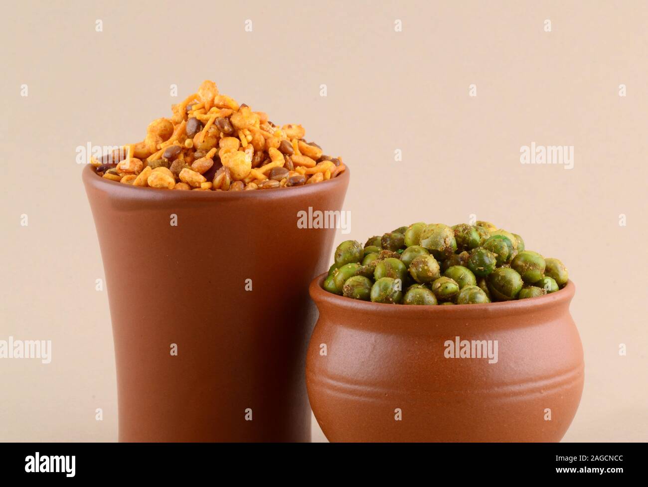 Indian snack: miscela e fritti speziati piselli verdi {chatpata mataró} in pentole di creta. Foto Stock
