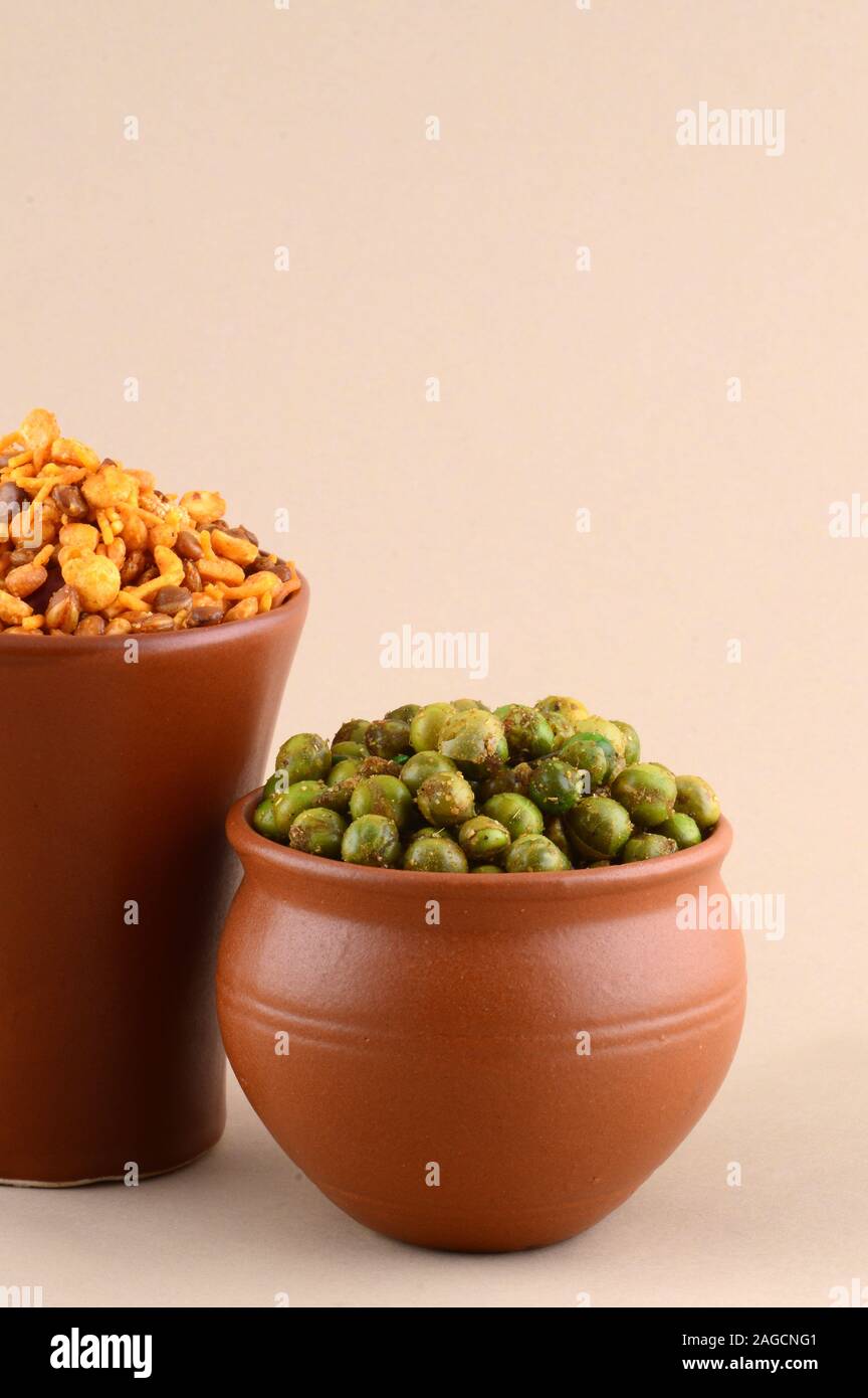Indian snack: miscela e fritti speziati piselli verdi {chatpata mataró} in pentole di creta. Foto Stock