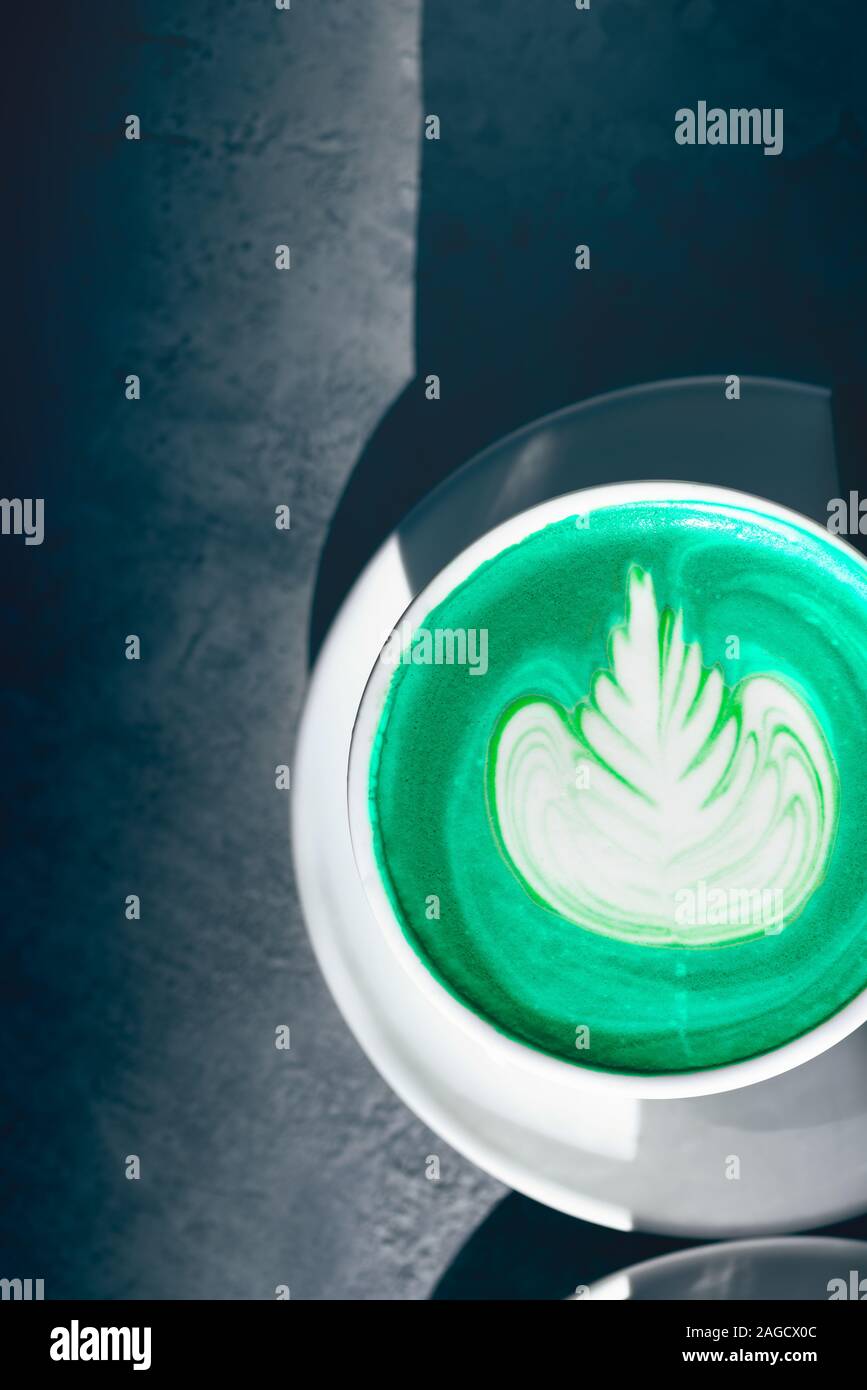 Tazza di Verde matcha latte nel caffè, bella giornata di sole, ombre sul tavolo Foto Stock