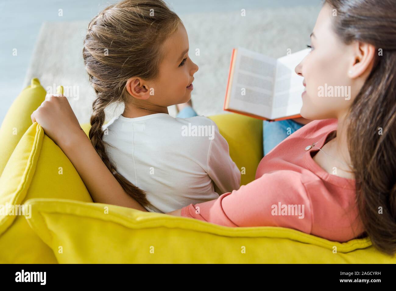 Messa a fuoco selettiva del bambino seduto sul divano con happy baby sitter azienda prenota Foto Stock