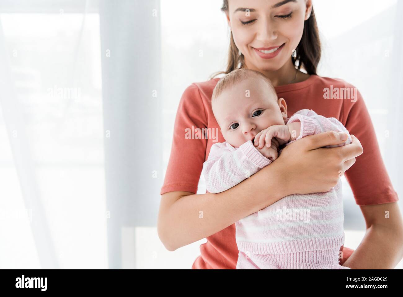 Sorridente madre tenendo in armi adorabile figlia bambino Foto Stock