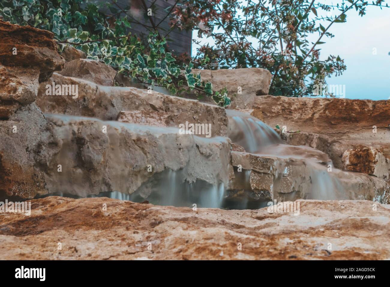 Una semplice cascata con alcuni vegetazione circostante. Bassa velocità otturatore Foto Stock