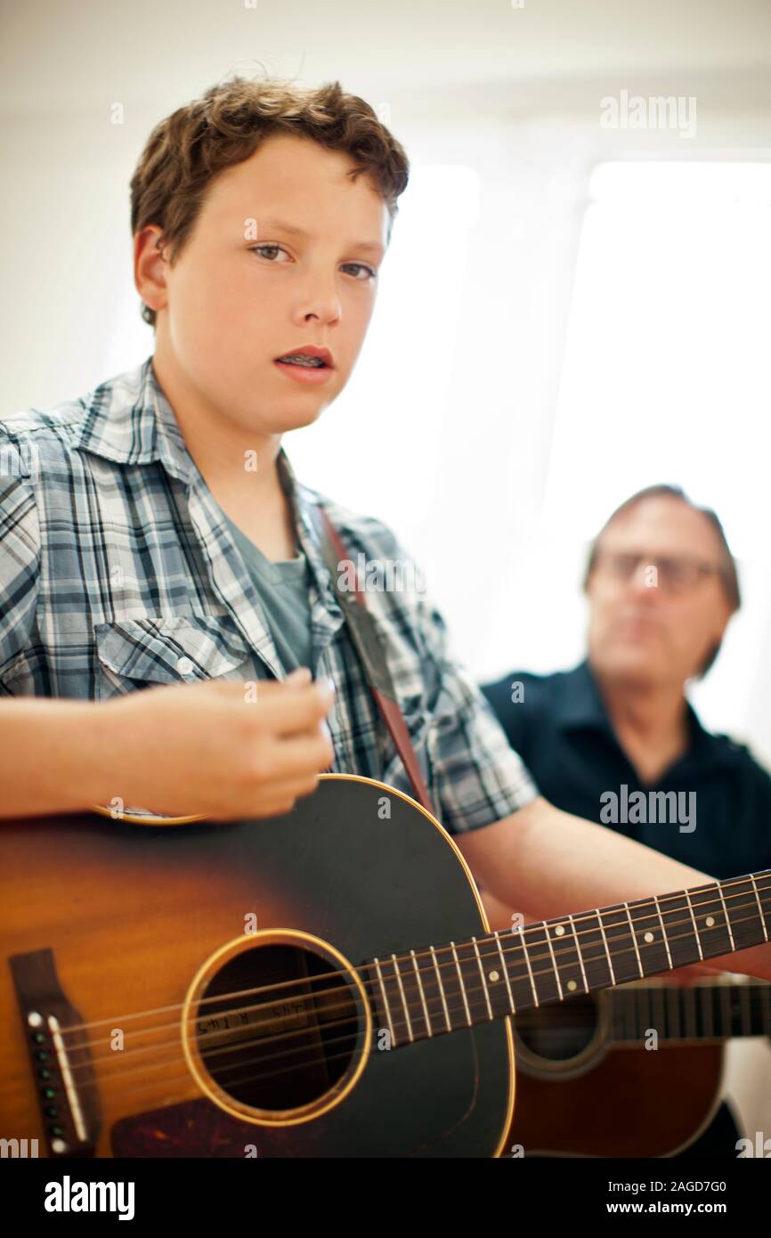 Ragazzo adolescente e uomo maturo la riproduzione di chitarre acustiche Foto Stock