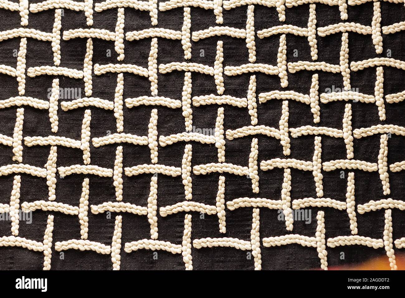 Bianco disegni ricamati su panno nero square Foto Stock