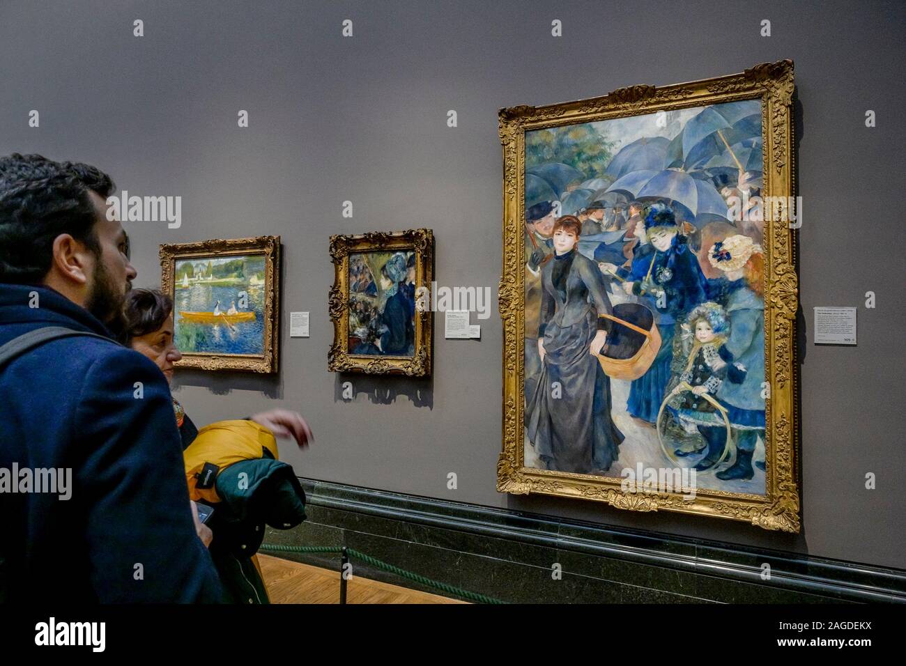 Guardando il dipinto di Renoir, gli ombrelli, la National Gallery, Londra, Inghilterra, REGNO UNITO Foto Stock