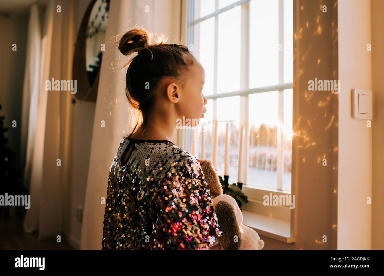 Giovane ragazza che gioca con il suo giocattolo a casa in un abito di scintillanti al tramonto Foto Stock