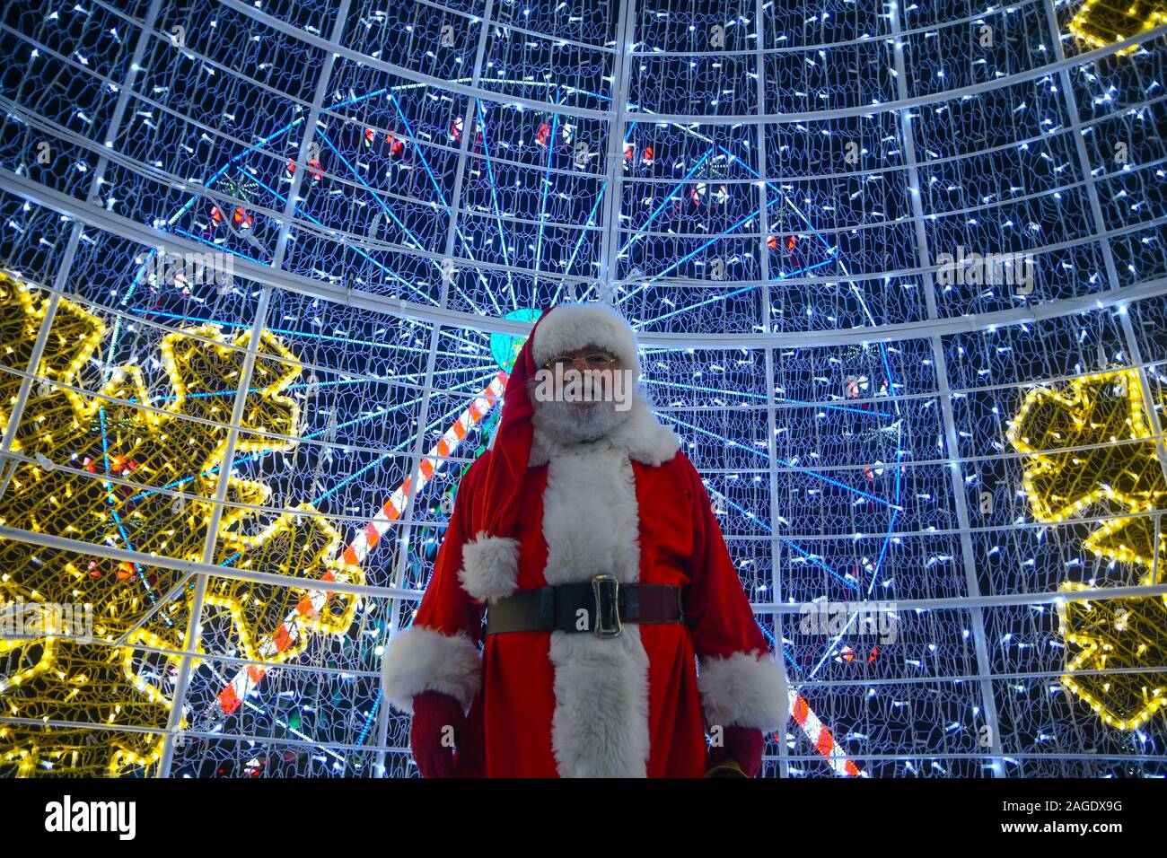 La Valletta, Malta. Xviii Dicembre, 2019. Un uomo vestito da Santa Claus si  erge di fronte colorate luci di Natale a La Valletta, Malta, il Dic. 18,  2019. Colorate luci di Natale