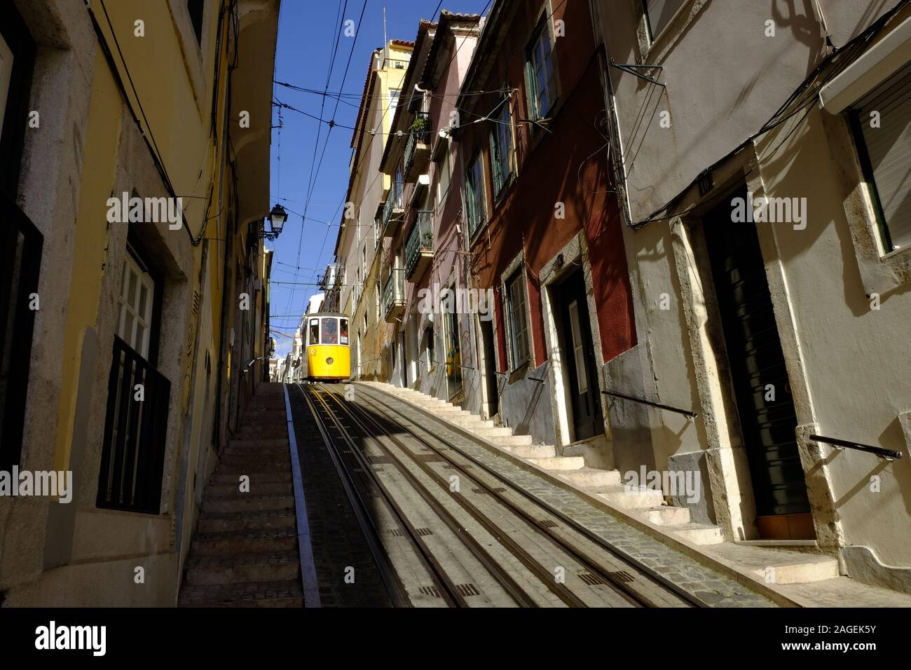 Foto a basso angolo del tram che attraversa le rotaie nella stretta strada di Lisbona, Portogallo Foto Stock