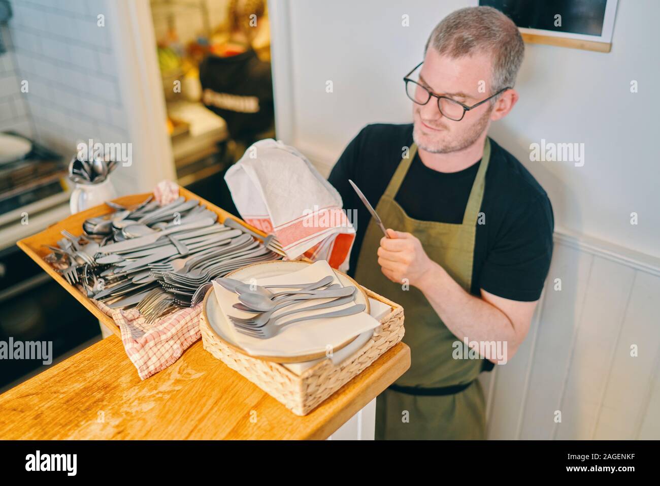 Cameriere tergi posate in ristorante Foto Stock