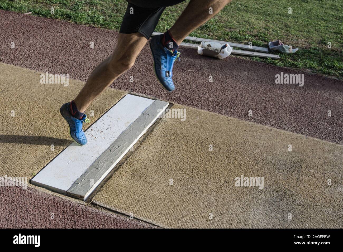 Uomo che si prepara a fare un lungo salto, piede sulla piastra di decollo. Foto Stock