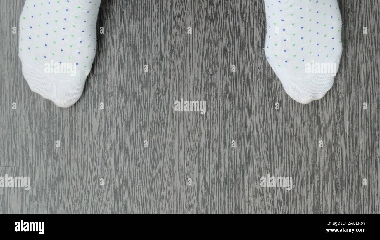 Punta di una coppia di calze bianche con modello punteggiato su un pavimento di legno, con copia spazio in mezzo. Foto Stock