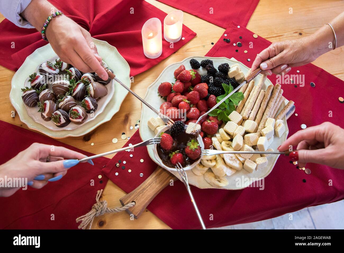 Vista aerea di mani frutto di immersione nella fonduta di cioccolato Foto Stock