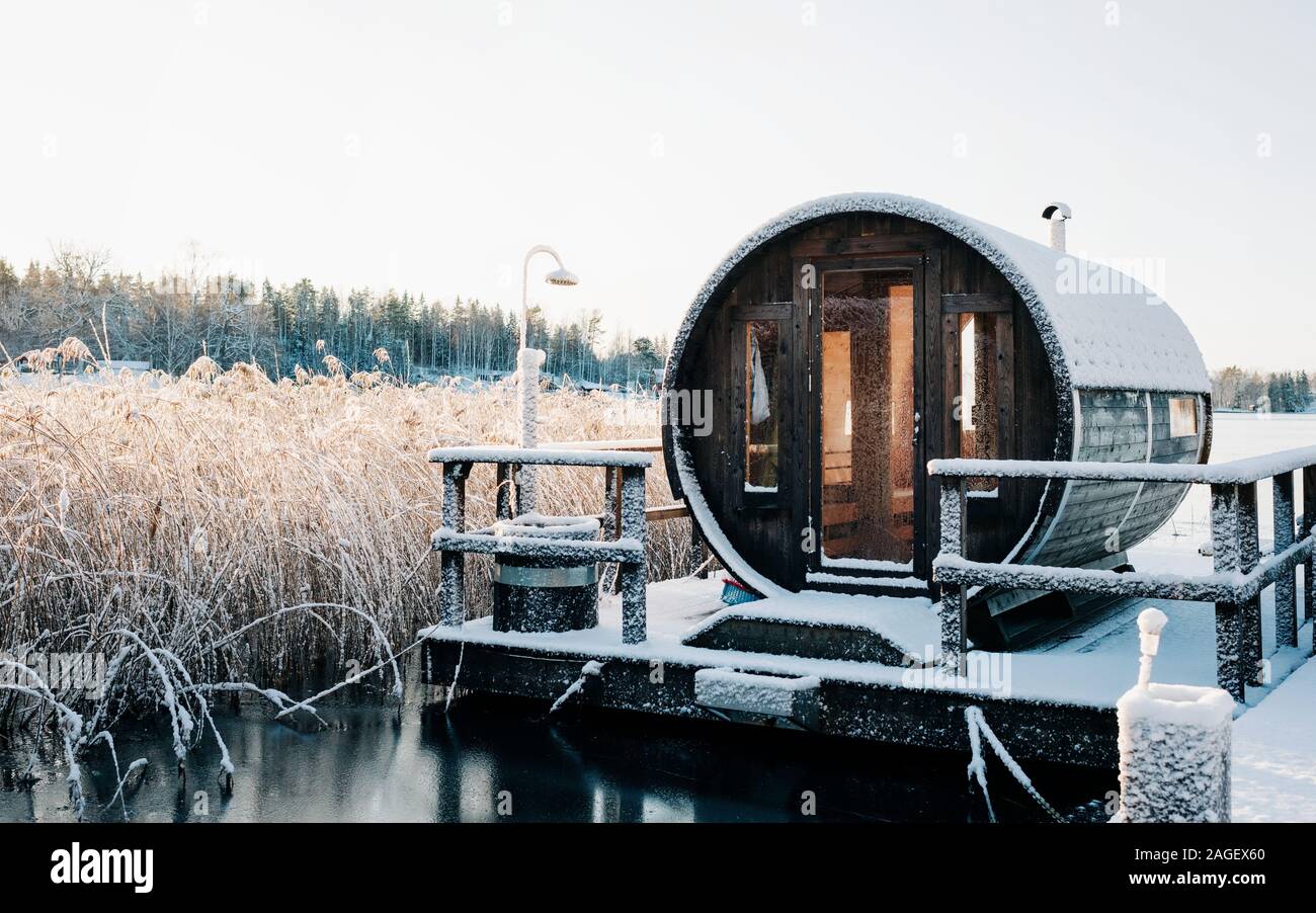 Sauna in legno su un pontile coperto di neve sulle sponde di un lago in Svezia in inverno Foto Stock