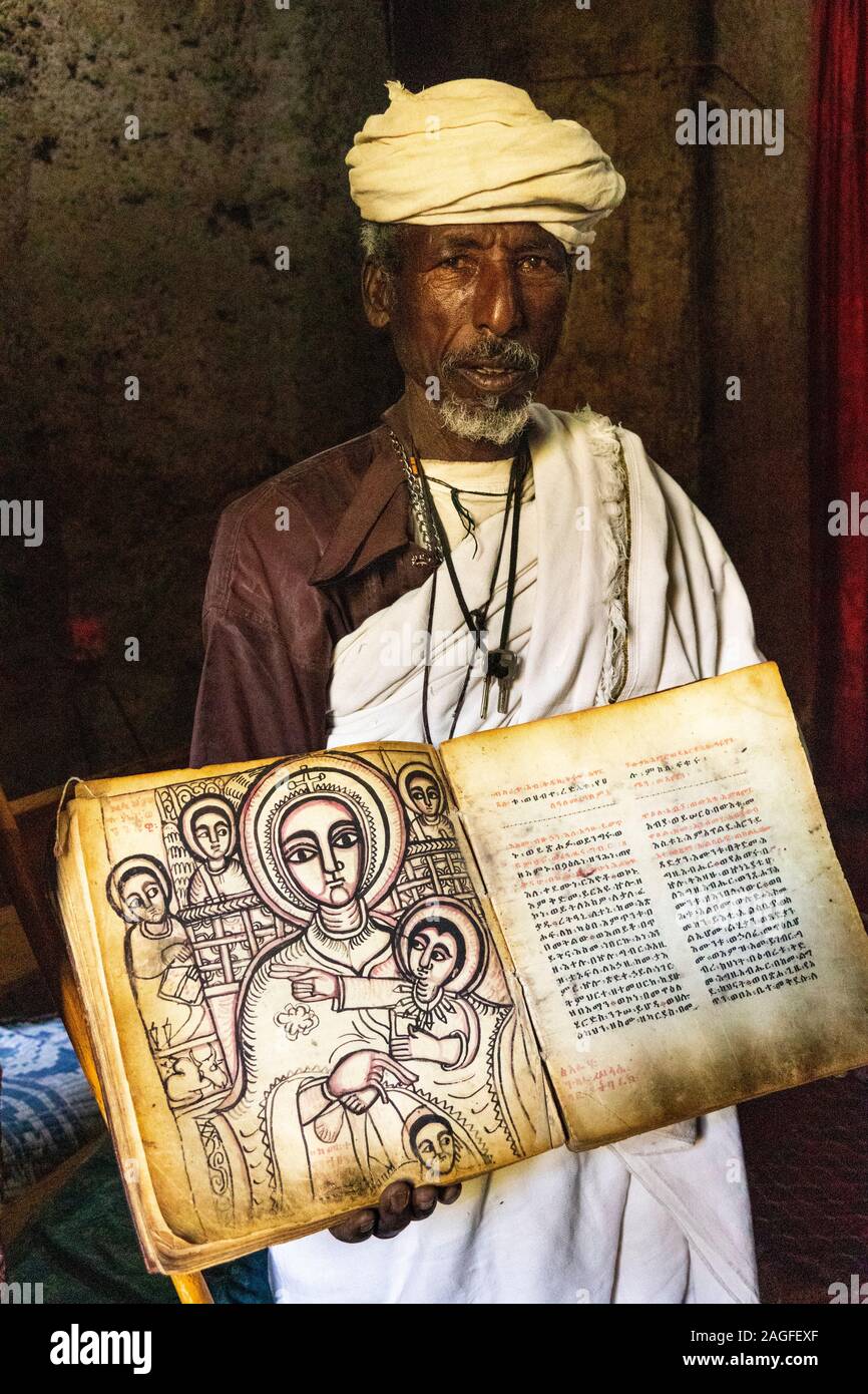 Etiopia, Amhara Region, Lalibela, Arbatu Ensessa, Biblia Chirkos, antiche rocce scavate chiesa, sacerdote mostra 800 anno-vecchio vangelo illuminato in Ge'ez s Foto Stock