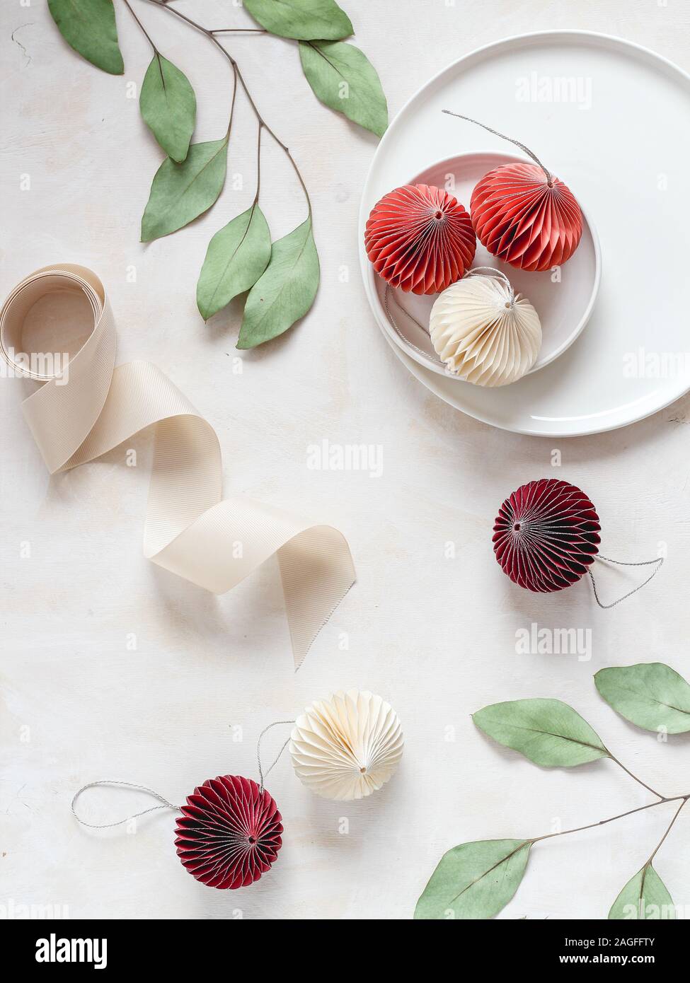 Ornamenti di Natale e nastro con ramificazione di eucalipto su uno sfondo luminoso. Stile flatlay Foto Stock