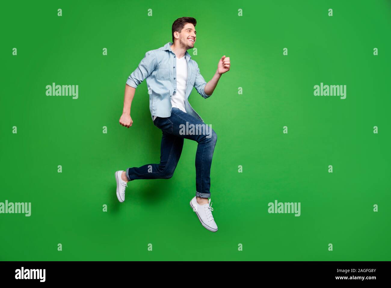 Lunghezza piena dimensione del corpo rivolta foto di allegro positivo funny man cerca di venire per le vendite in tempo di salto isolato in esecuzione su verde colori vividi Foto Stock