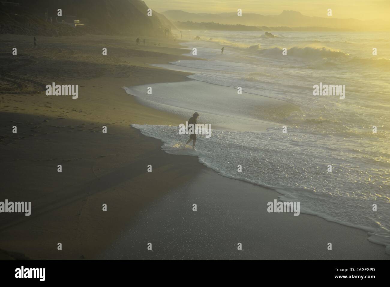 Uomo in un tappo piatto con i suoi pantaloni arrotolato paddling in onde dell'oceano, pasakdek Foto Stock