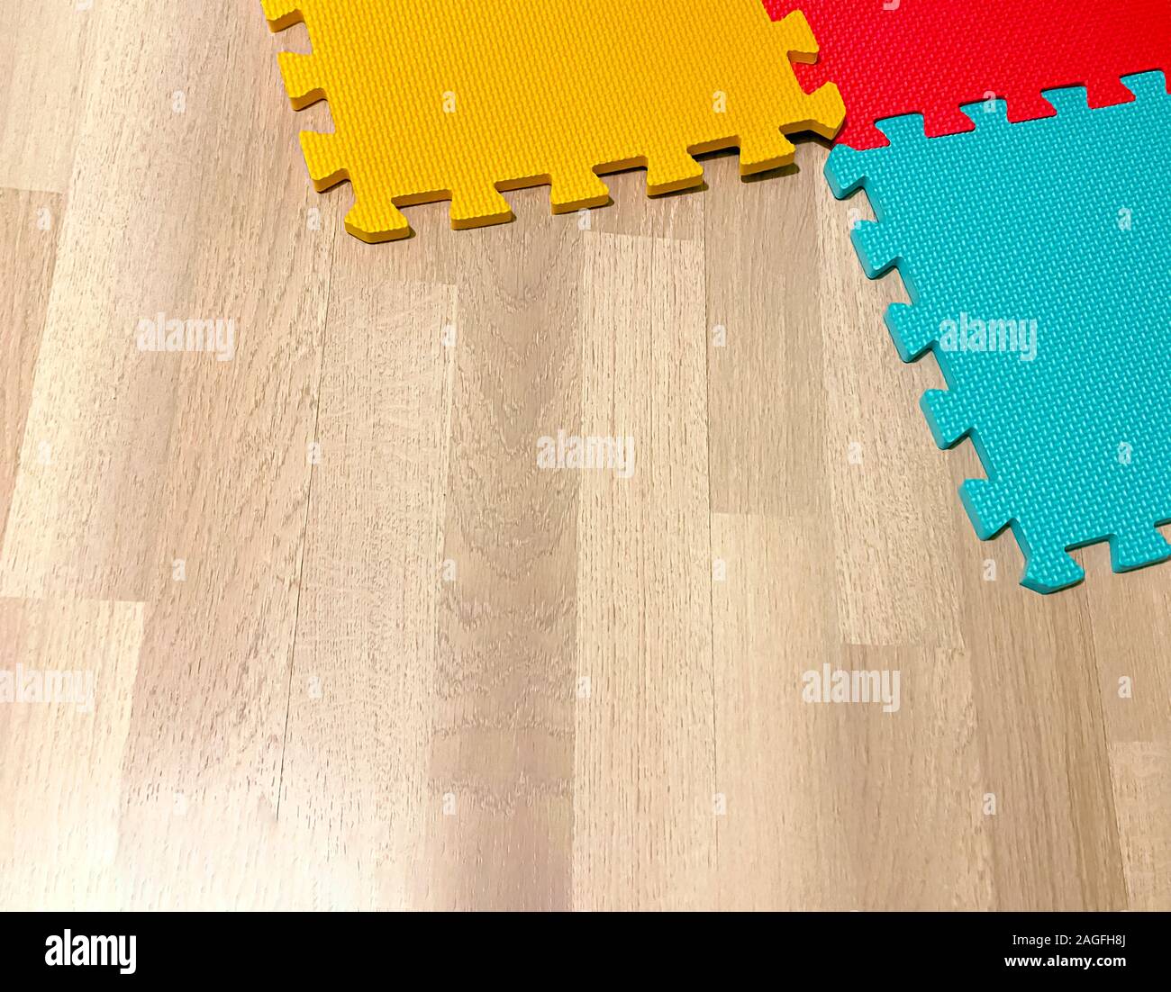 Morbido tappetino di gomma composta da blocchi colorati intersecato con ogni altro su di un pavimento in legno. Adatto per far giocare i bambini o per gli esercizi di yoga. Interio Foto Stock