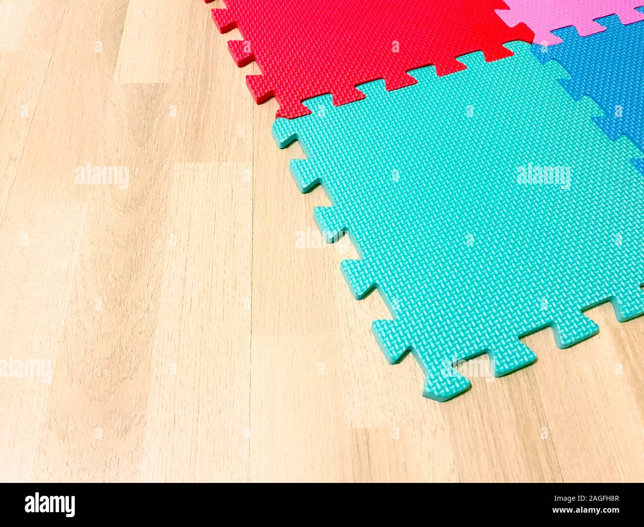 Morbido tappetino di gomma composta da blocchi colorati intersecato con ogni altro su di un pavimento in legno. Adatto per far giocare i bambini o per gli esercizi di yoga. Interio Foto Stock