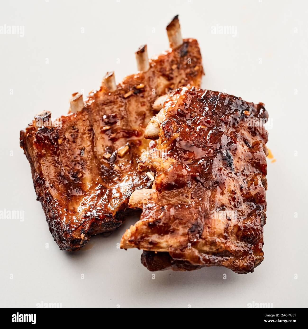Due appiccicosa piccante grigliate di porzioni delle nervature di un barbecue su uno sfondo bianco in stretta fino a menu pubblicità Foto Stock