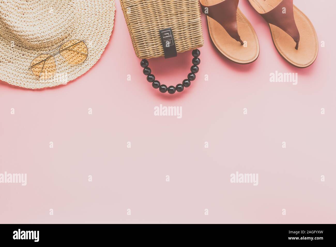 Moda estate su sfondo rosa, trendy borsa di paglia, fedora hat, sandali di cuoio e occhiali da sole giallo, piatto di laici che, vista dall'alto, il fuoco selettivo Foto Stock