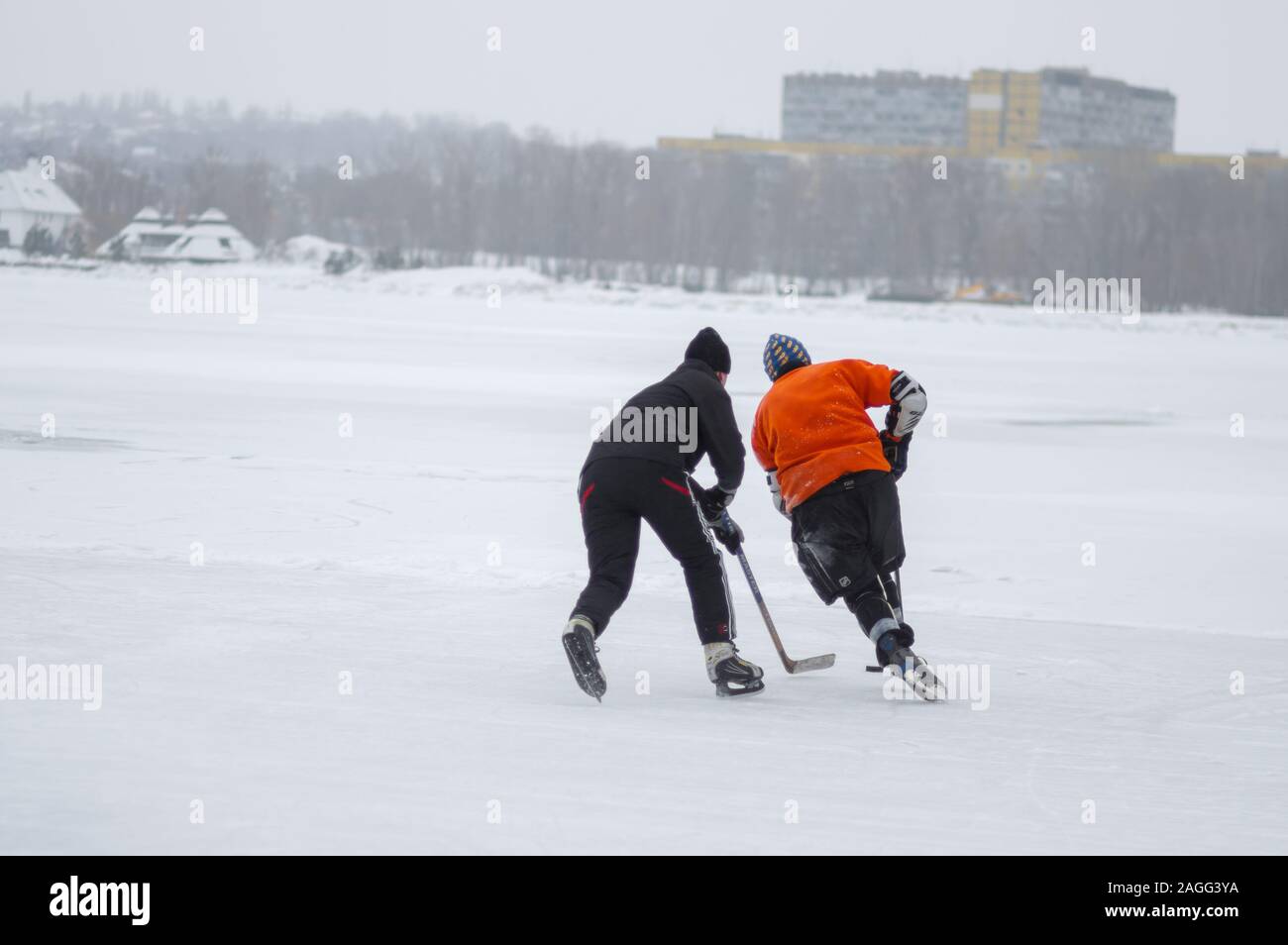 Dnipro, Ucraina - 28 Gennaio 2018: adolescente in lotta con papà per la confezione durante il gioco di hockey su un fiume congelato Dnipro in Ucraina Foto Stock