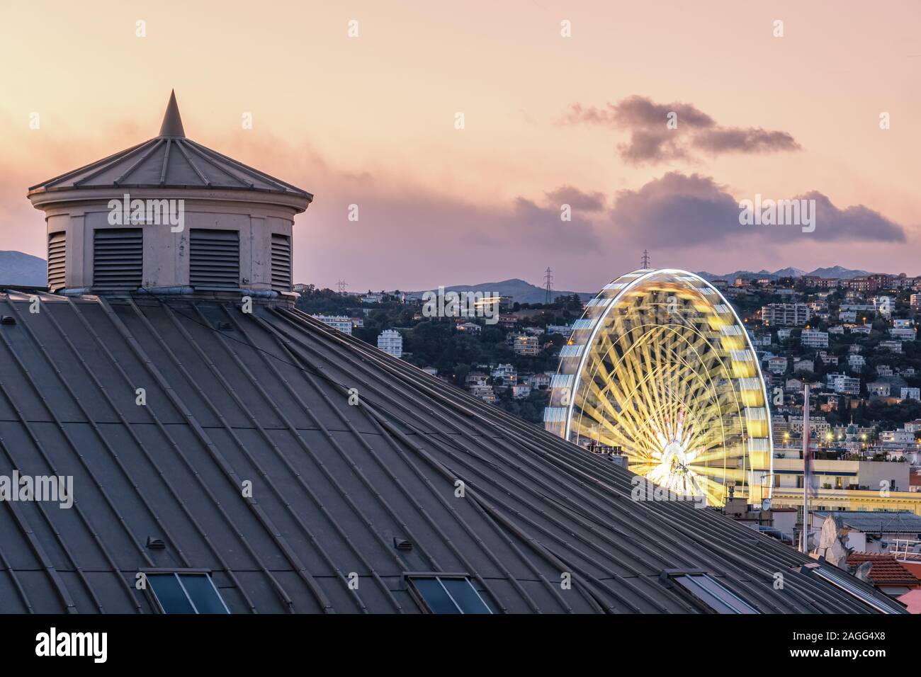 Tetto della bella Opera House al tramonto con una grande ruota illuminata la filatura in background e delle montagne innevate della distanza Foto Stock