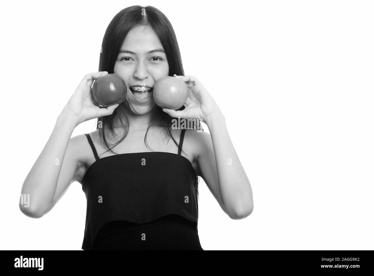 Giovani asiatici felice ragazza sorridente mettendo in rosso e verde mela sul viso Foto Stock