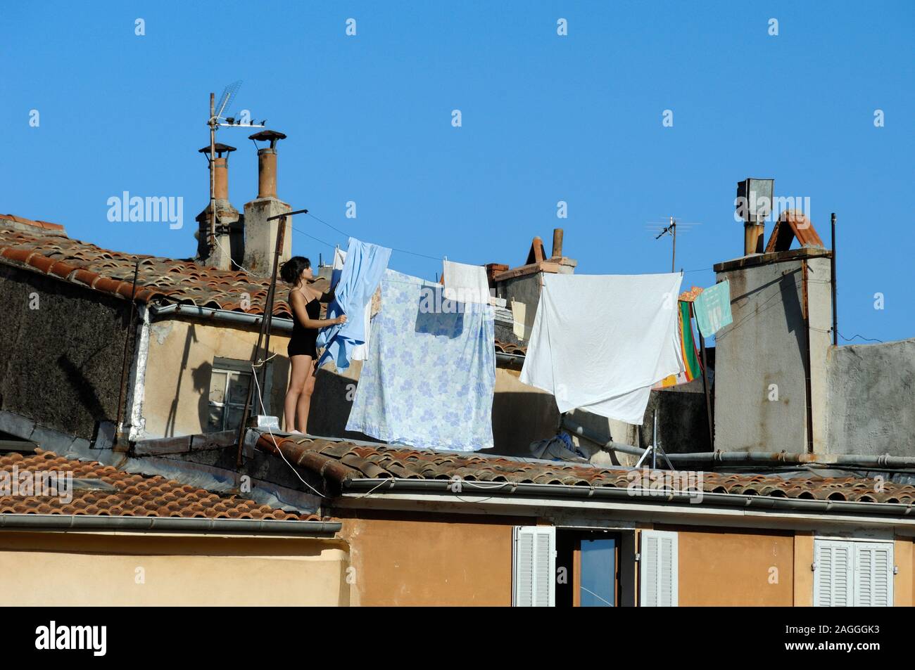 Giovane donna appendere fuori il lavaggio a secco sulla linea di lavaggio o linea di abbigliamento sui tetti di Aix-en-Provence Provence Francia Foto Stock