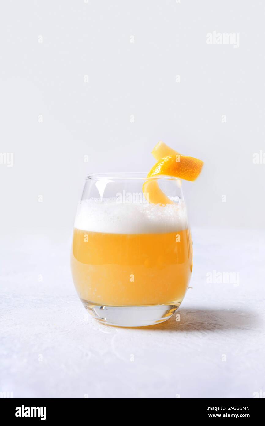 Il whiskey sour cocktail - bourbon con il succo di limone e lo sciroppo di zucchero e albume in vetro su bianco. Formato verticale. Uno shot. Foto Stock