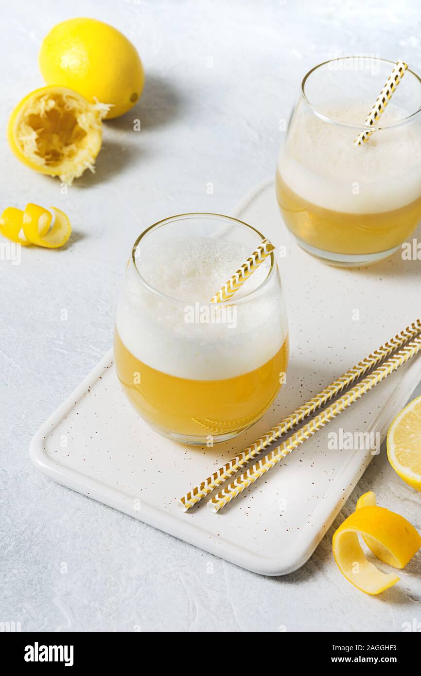 Il whiskey sour cocktail - bourbon con il succo di limone e lo sciroppo di zucchero e albume in vetro su bianco. Close up. Orientamento verticale. Foto Stock