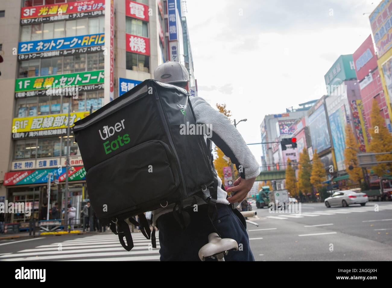 Tokyo, Giappone. Xviii Dicembre, 2019. Un Uber mangia ciclista passeggiate attraverso Chuo-dori Avenue cross road a Akihabara, Tokyo.Akihabara, chiamato anche Akiba dopo un ex santuario locale, è un quartiere centrale di Tokyo che è famosa per i suoi molti negozi di elettronica. In anni più recenti, Akihabara ha guadagnato il riconoscimento come il centro del Giappone otaku (i cultori del ventilatore) cultura e molti negozi e stabilimenti dedicati alle anime e manga ora sono dispersi tra i negozi di elettronica nel distretto. Credito: Stanislav Kogiku SOPA/images/ZUMA filo/Alamy Live News Foto Stock