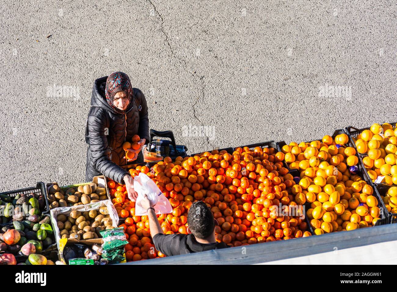 Capileira, La Alpujarra, Alpujarras, regione di Granada, Andalusia, Spagna. La donna acquista le arance e sacchetto di plastica al mercato nel villaggio. Foto Stock