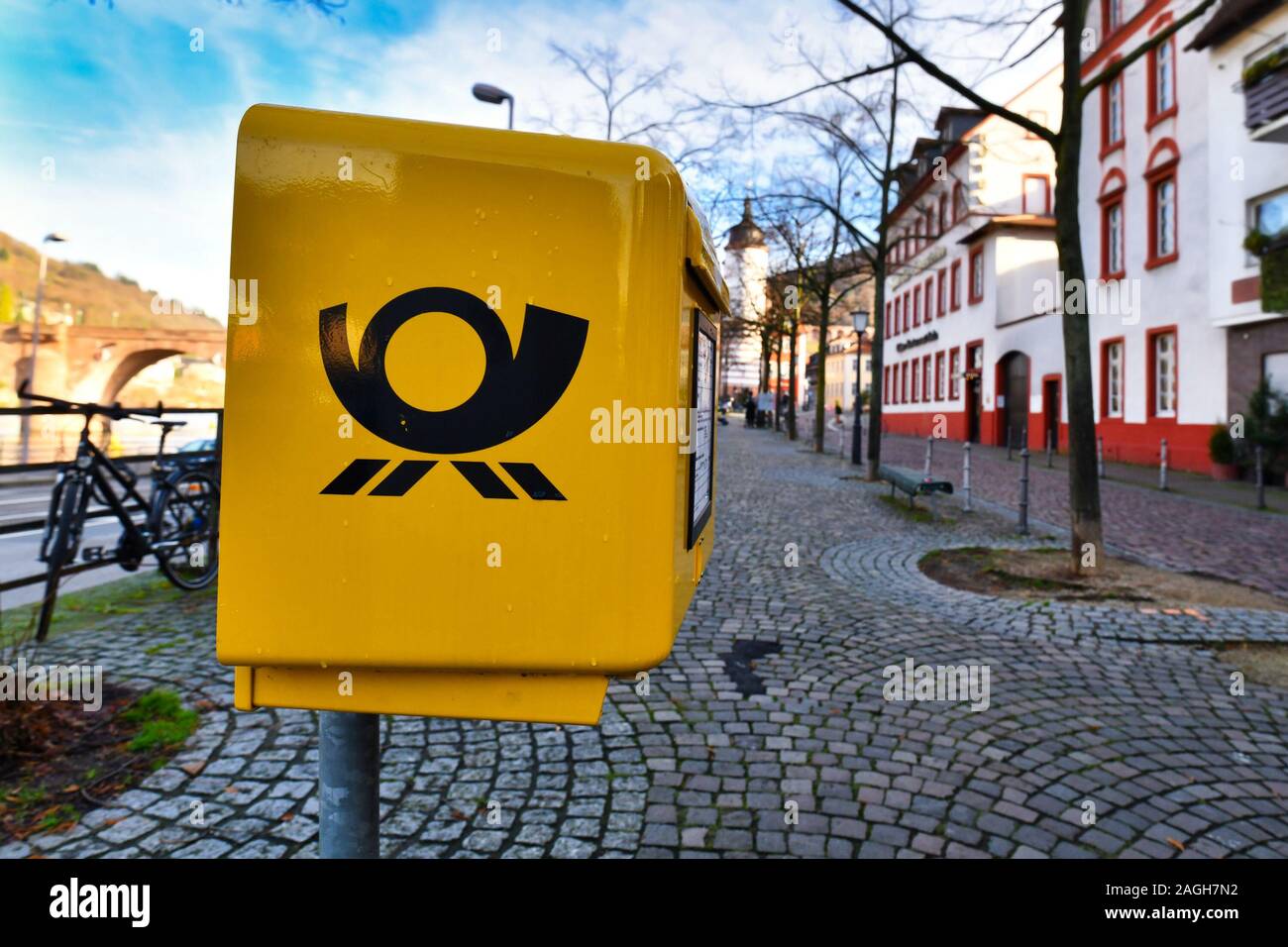 Heidelberg, Germania - Dicembre 2019: Giallo funzionario pubblico tedesco casella posta nella parte anteriore del sfocata strada di città Foto Stock