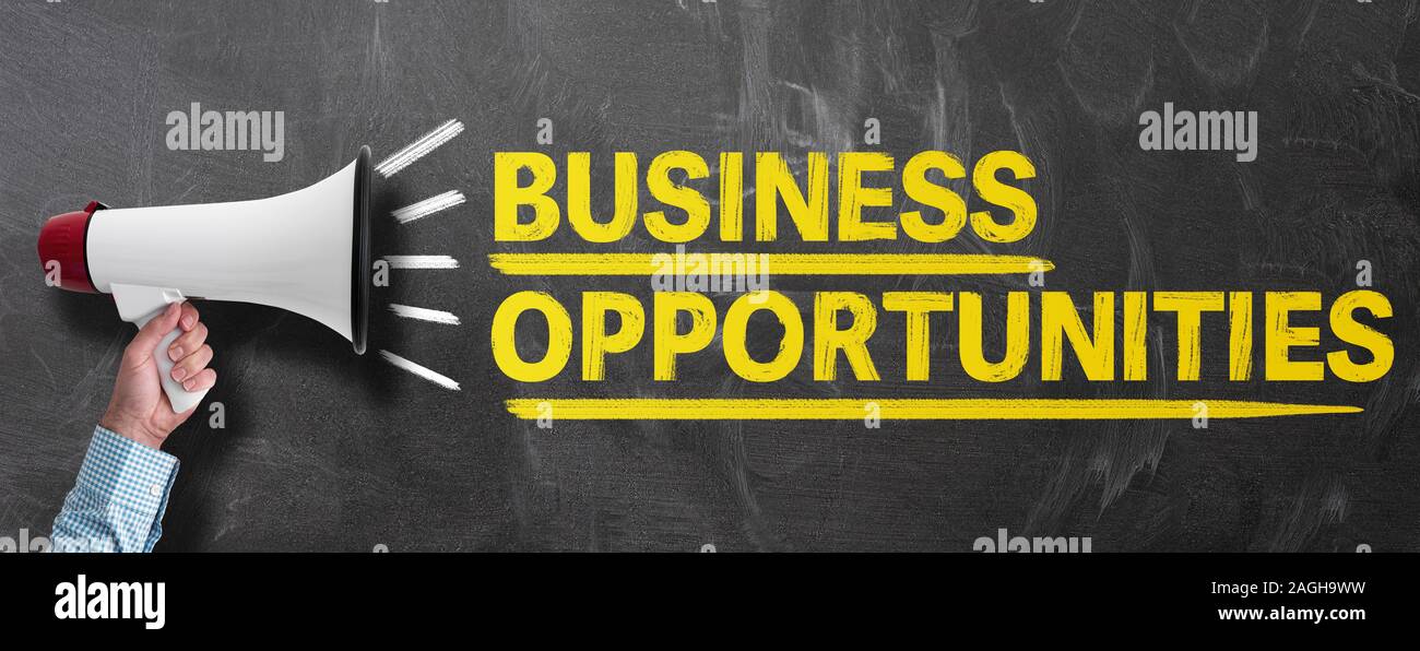 Mano azienda megafono o bullhorn contro la lavagna con testo di opportunità di business Foto Stock