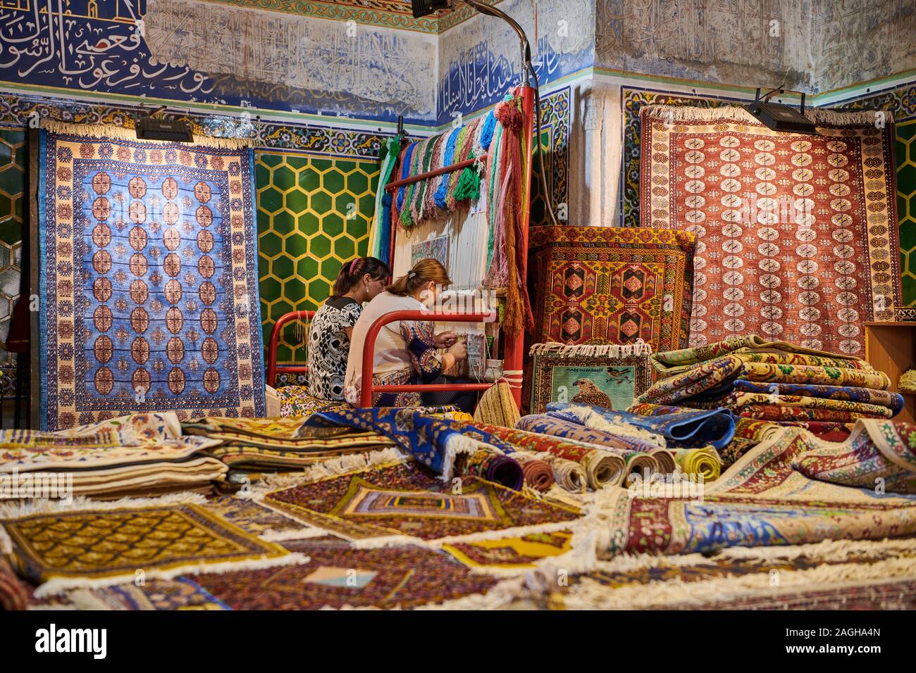 La tessitura dei tappeti le donne all'interno Sher-Dor Madrasah, famoso Registan di Samarcanda, Uzbekistan in Asia centrale Foto Stock