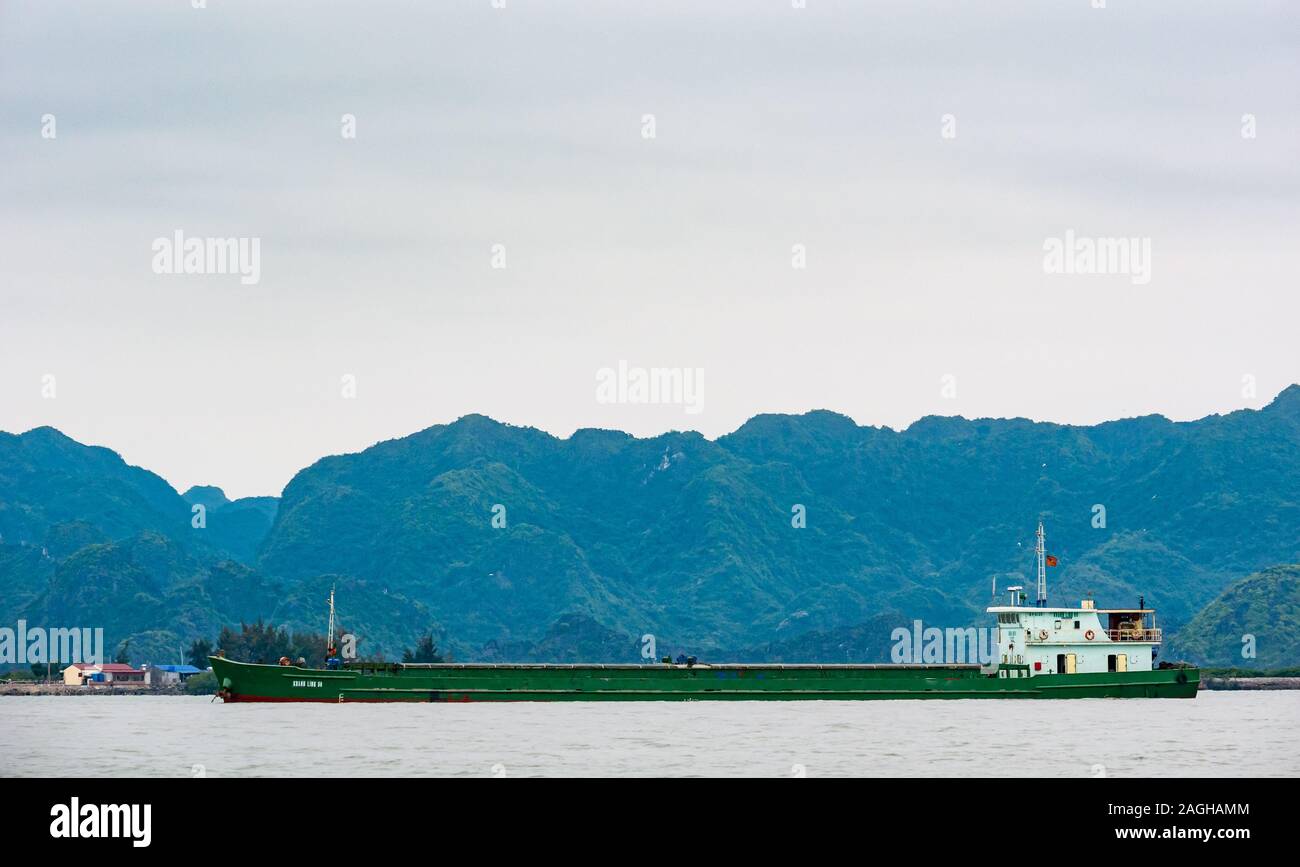 Basso river barge con le montagne sullo sfondo di Halong Bay, Haiphong, nel Vietnam del nord, sud-est asiatico Foto Stock