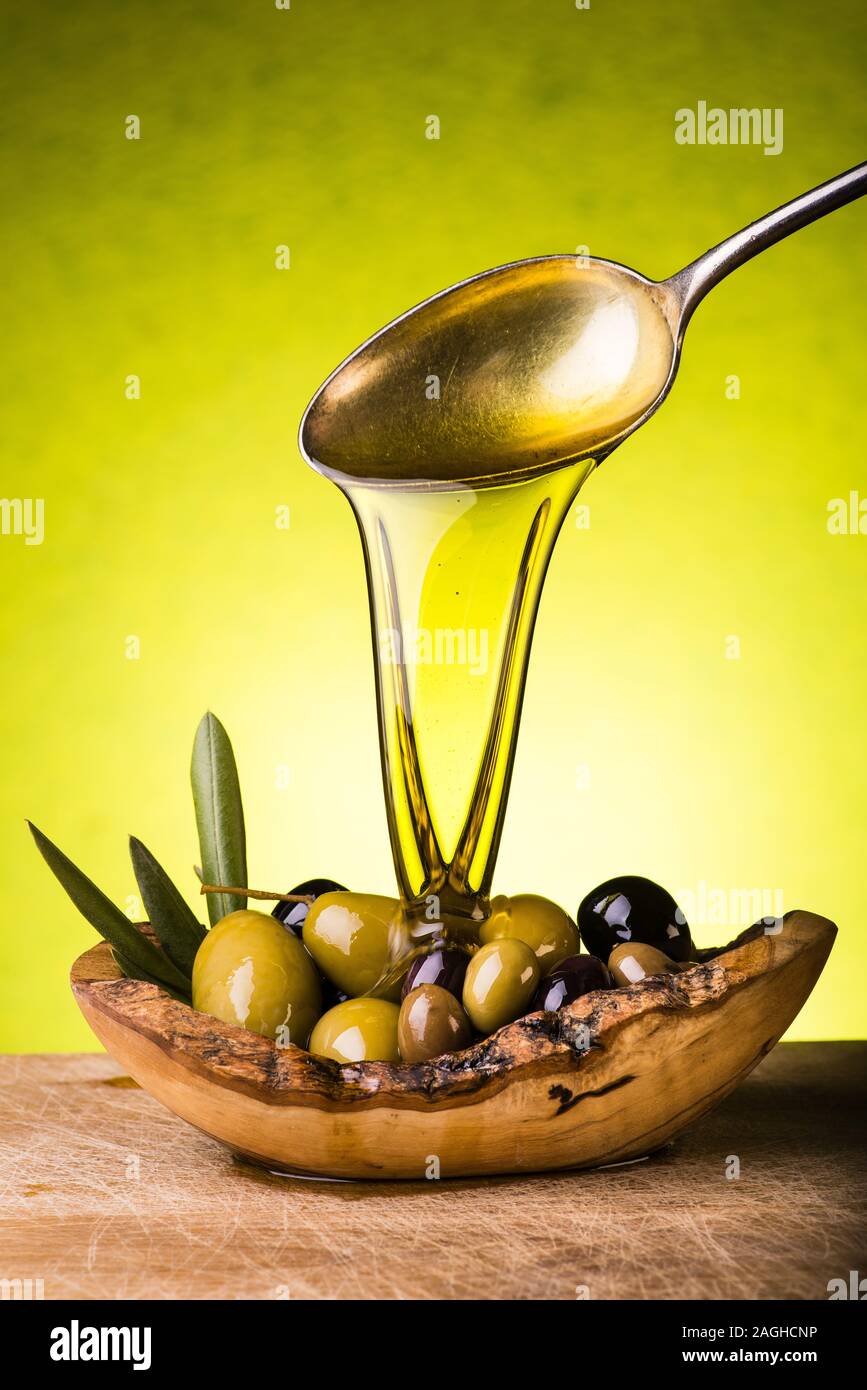 Un cucchiaio di olio viene versata sul recipiente contenenti differenti tipi di olive Foto Stock