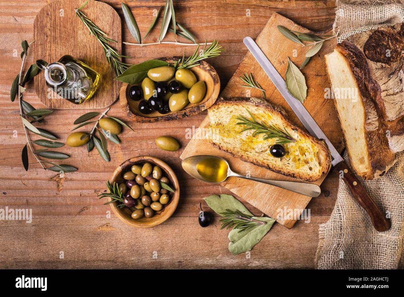 Sulla tavola in legno rustico, un cucchiaio pieno di olio delle olive e fette di pane Foto Stock