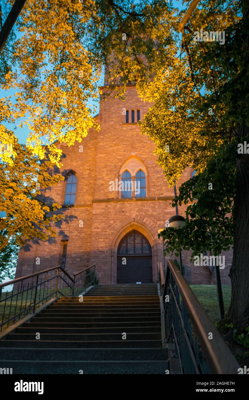 Vista panoramica di foglie di albero illuminato da fasci di luce in prossimità di una chiesa in Germania Foto Stock