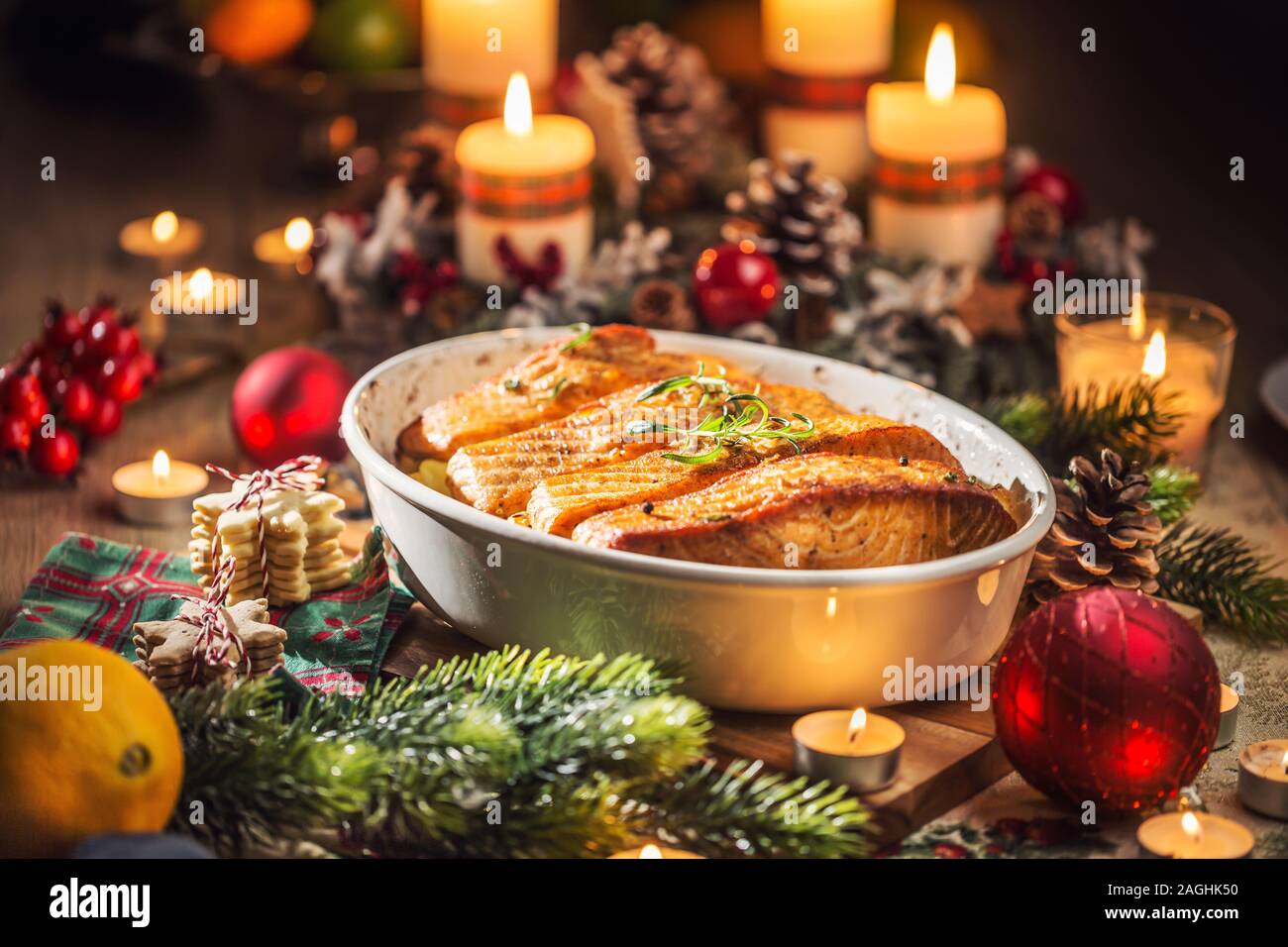Cena di Natale da pescare il salmone nel piatto di torrefazione con decorazione di festa corona di Avvento e candele. Foto Stock