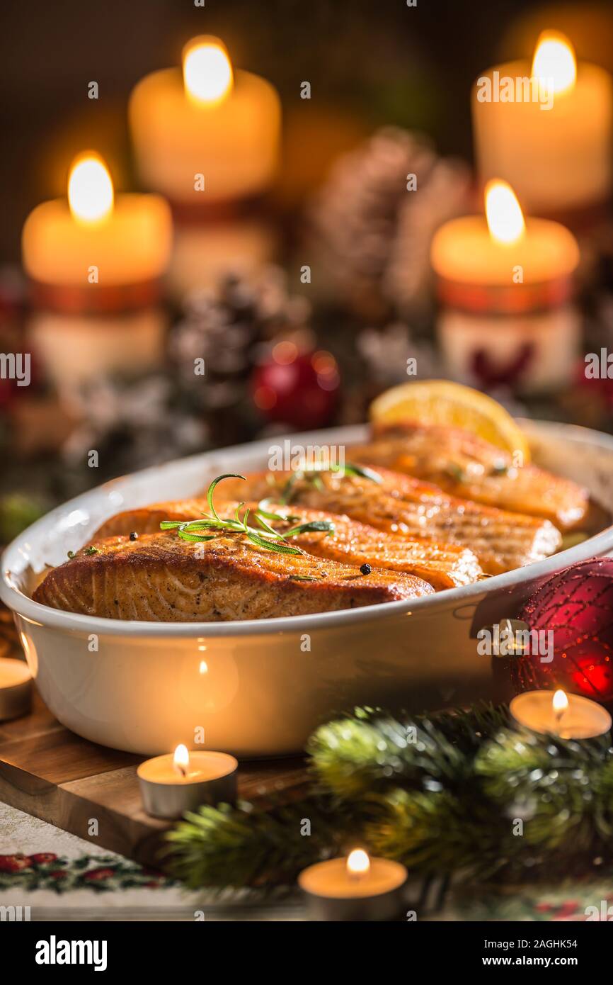Cena di Natale da pescare il salmone nel piatto di torrefazione con decorazione di festa corona di Avvento e candele. Foto Stock