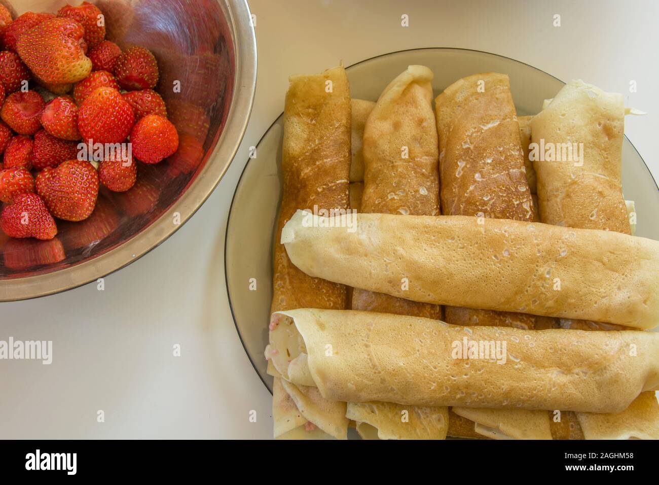 Le fragole in un recipiente di alluminio e frittelle di laminati su una piastra Foto Stock