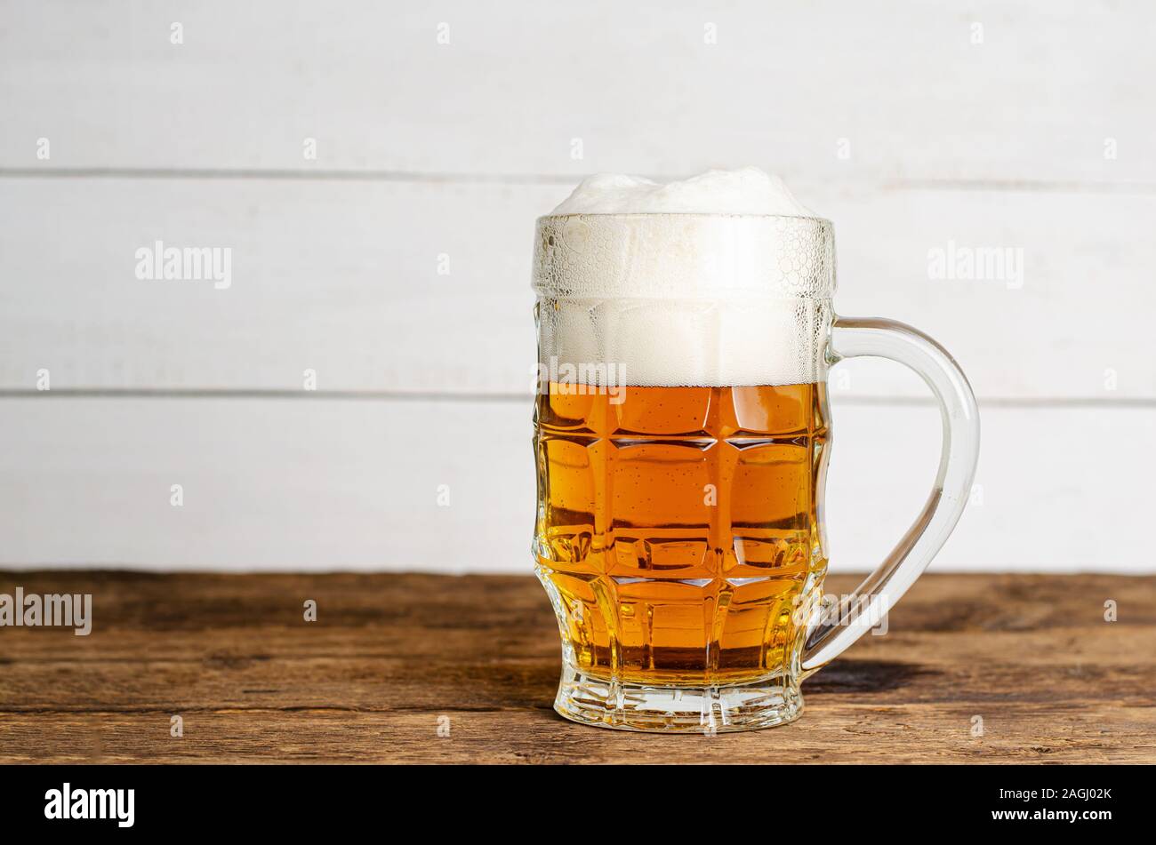 Bicchiere pieno di birra bionda su bianco backgroud in legno. Spazio di copia Foto Stock