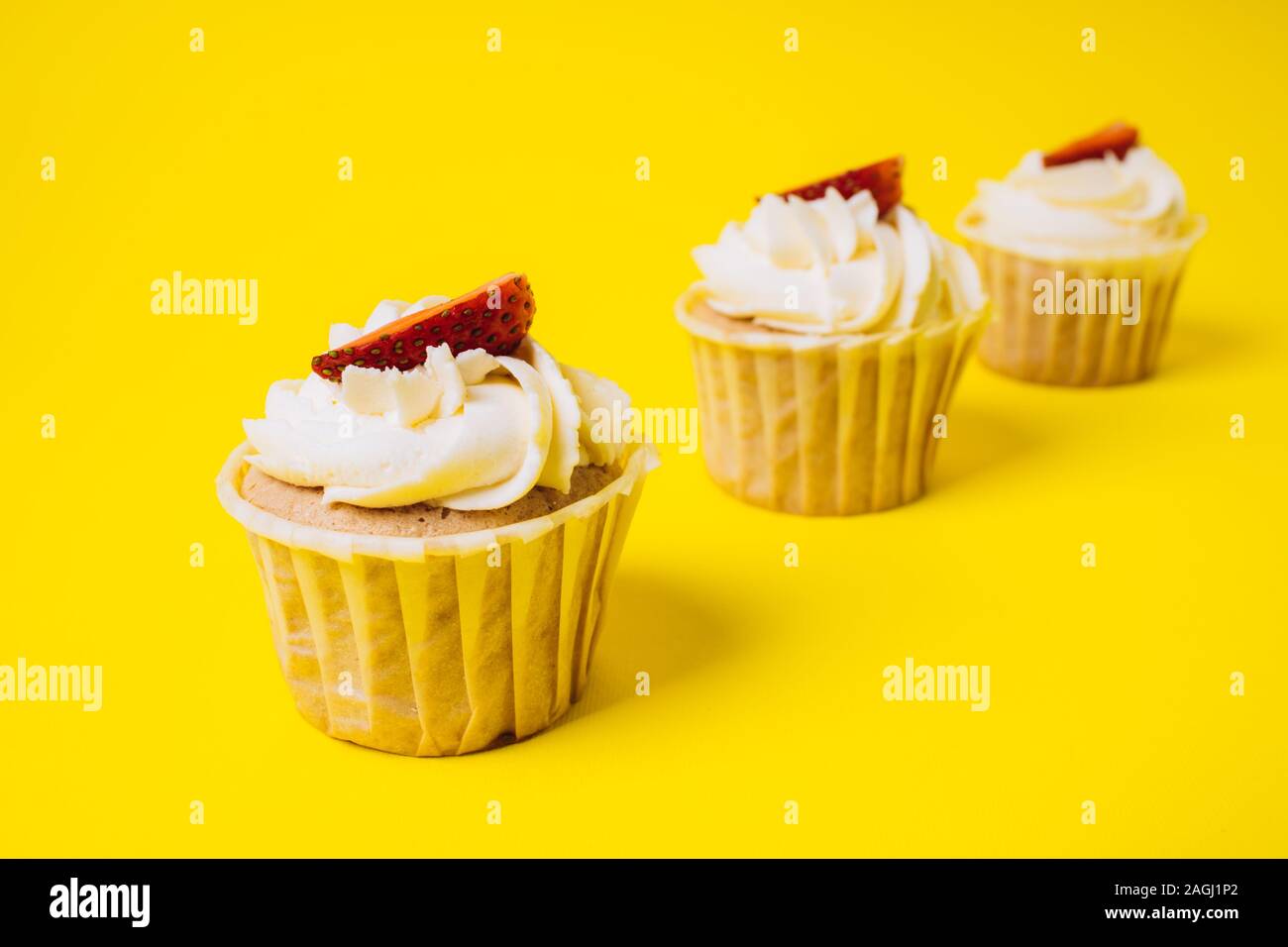 Torte con crema bianca e fragola ripieno su uno sfondo giallo. Cottura e dolci. Foto Stock