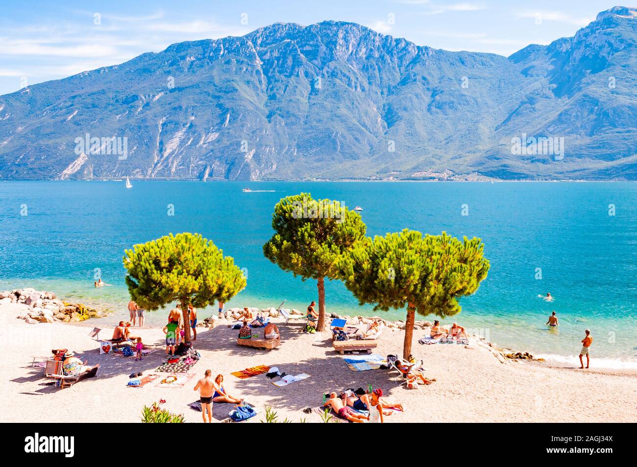 Limone sul Garda, Lombardia, Italia - 12 Settembre 2019: accogliente spiaggia sulla costa occidentale del lago. La gente di nuoto a prendere il sole sulla riva sotto alta ev Foto Stock