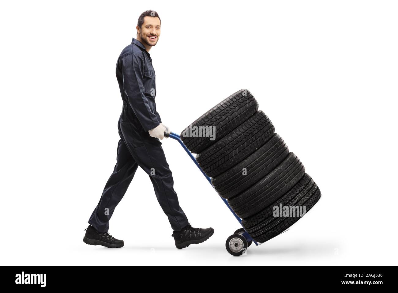 A piena lunghezza shot di un lavoratore spingendo un carrello con gli pneumatici per auto isolati su sfondo bianco Foto Stock