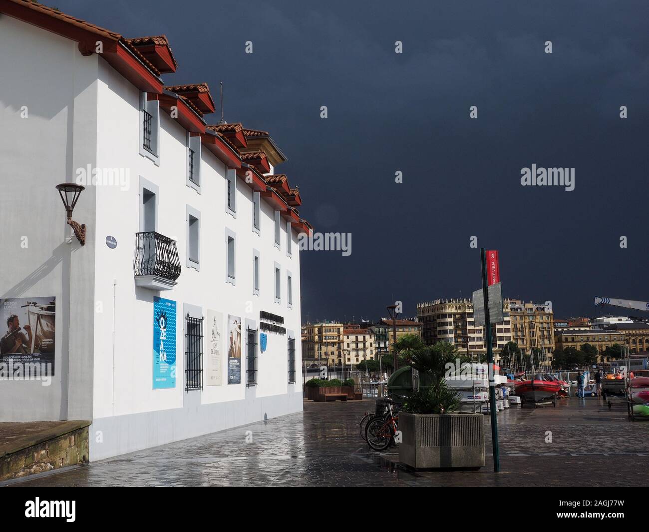 Cielo scuro di imminente tempesta su soleggiati edificio bianco sul lungomare di Marina di San Sebastian, nel nord della Spagna, Europa Foto Stock